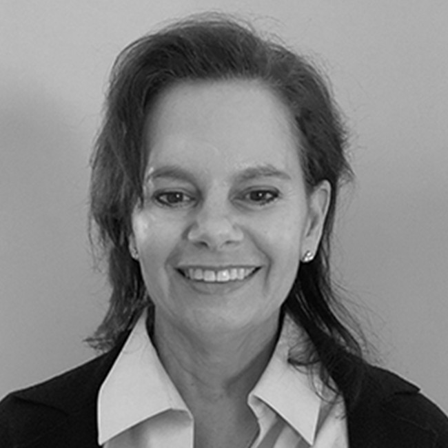 An image of a smiling adult woman named Kim Batarse, who is a director on the Business and Program development team at the Milken Institute. The image is black and white and she has shoulder-length seemingly brunette hair, white skin, and is wearing a white collared shirt.