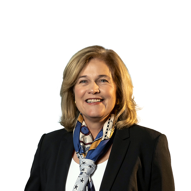An image of a woman named Jenny Johnson. She has white skin, shoulder-length blonde hair, and is wearing a colorful scarf and black blazer against a white background.