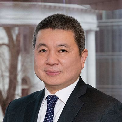 Professional headshot of an Asian businessman in a dark suit and striped tie