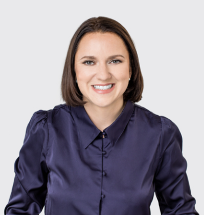 Professional headshot of a smiling woman in a navy blue button-down shirt against white background