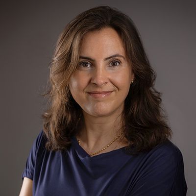 Professional headshot of a woman with shoulder-length brown hair wearing a blue top