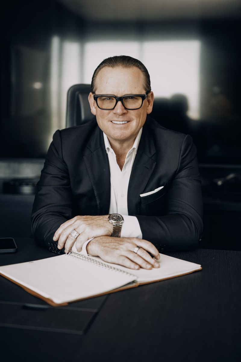Professional man in glasses and suit sitting at desk with documents in modern office