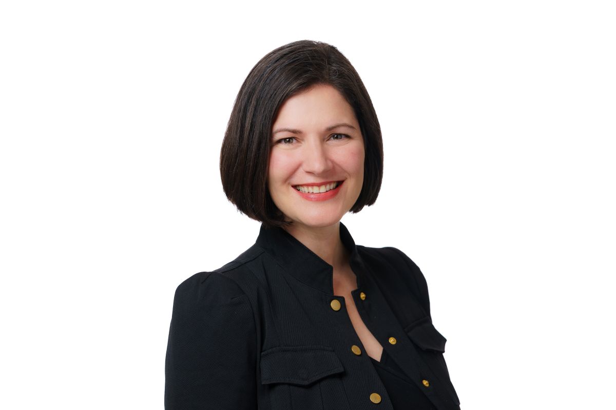 Professional woman with short dark hair wearing black business suit, smiling warmly