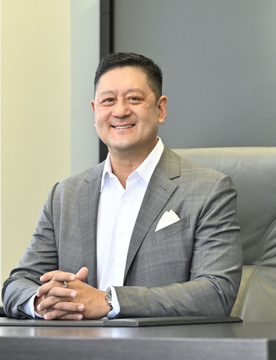 Professional man in gray suit smiling while seated at desk