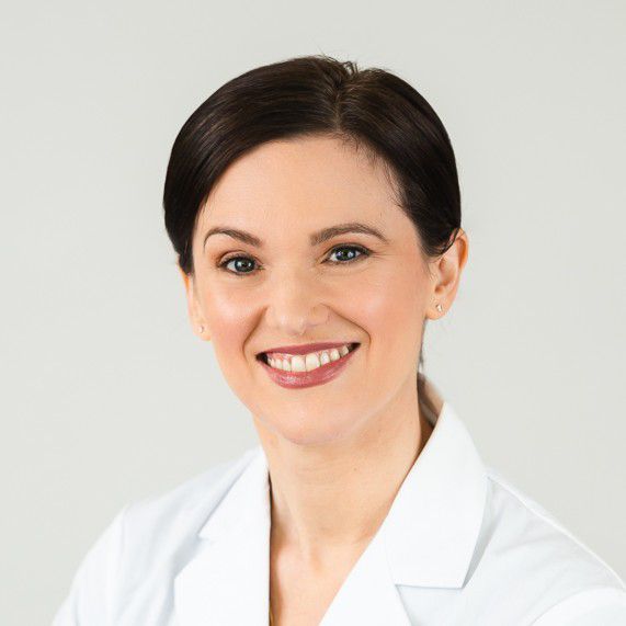 Professional headshot of smiling woman against light gray background