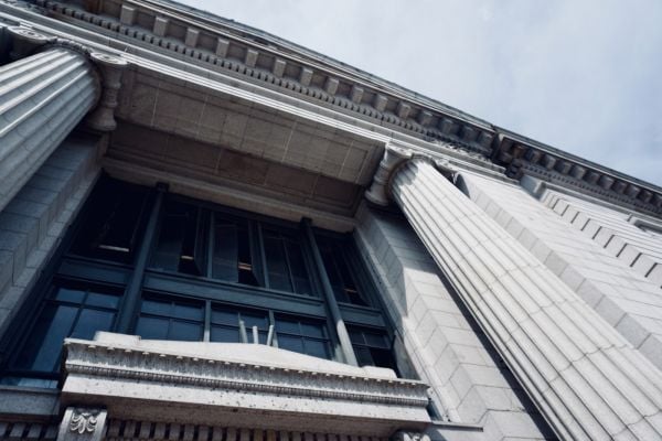 A photograph of a building with large columns in the front, shot from the ground looking upward to the sky