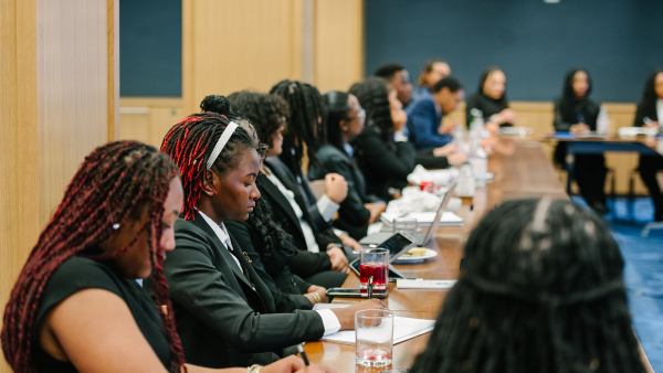 An image of HBCU 2025 Cohort Class Sessions. The Milken Institute's Inclusive Capitalism Program Insights' Team Hosts 2025 HBCU Fellows in Washington, DC. There is a diverse group of young people sitting at a long table and taking notes.