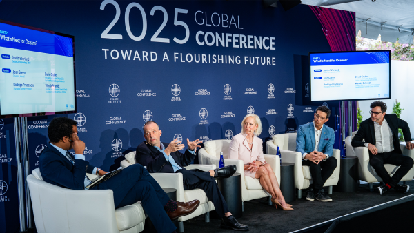 An image of a diverse group of adults sitting in white chairs on a stage at the Milken Institute's Global Conference 2025.