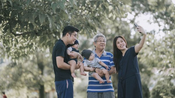 Family taking a selfie together in a sunny park.