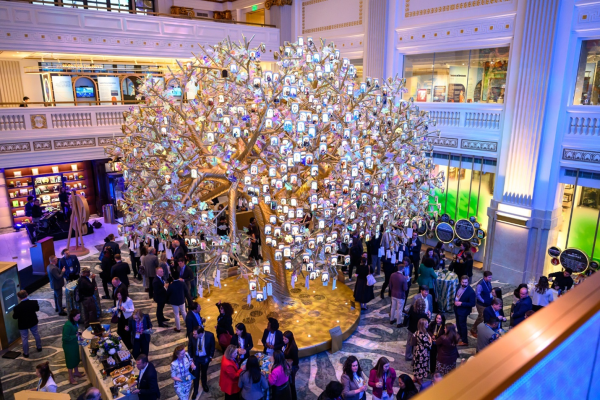 A high-angle wide shot of a crowded evening reception in a grand, neoclassical hall.