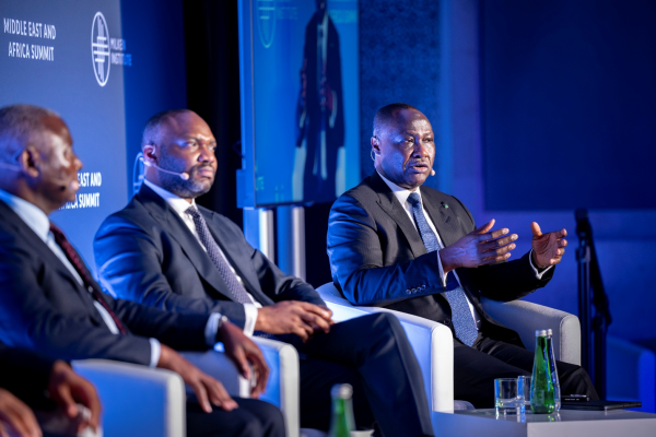 Three professional men in suits participate in a panel discussion at the Milken Institute Middle East and Africa Summit.