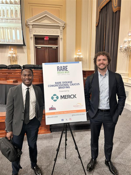 Two people standing next to a sign