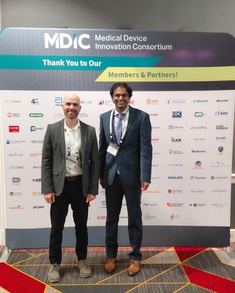 Two men in business attire standing together at MBIC Medical Device Innovation Consortium event