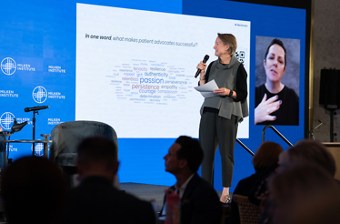 Business presenter speaking on stage with slide projection and audience silhouettes in foreground