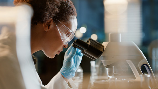 Student with curly hair looking through microscope in classroom laboratory setting