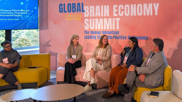 Panel discussion at Global Brain Economy Summit with six participants seated on colorful chairs