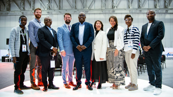 Group of eight diverse professionals standing together in a bright modern office space