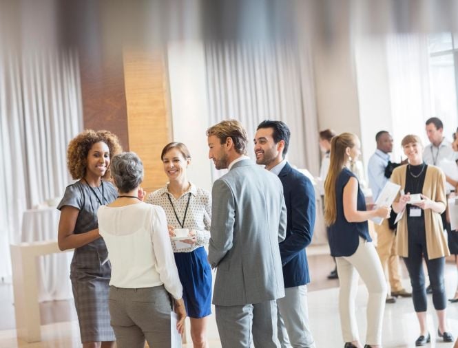 Several people in business attire networking at a conference