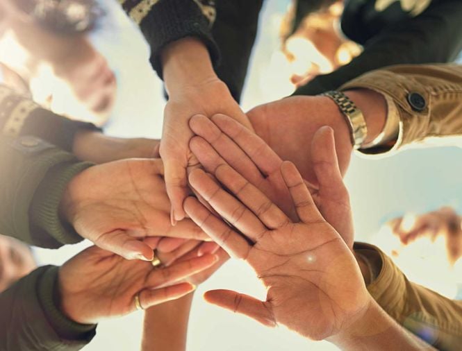 Multiple hands touching in a circle on a sunny day