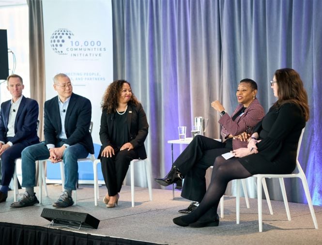 A diverse group of people sit on stage in a discussion