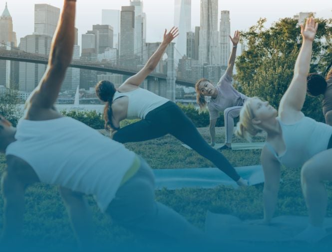 A group of people do yoga outside in a park together