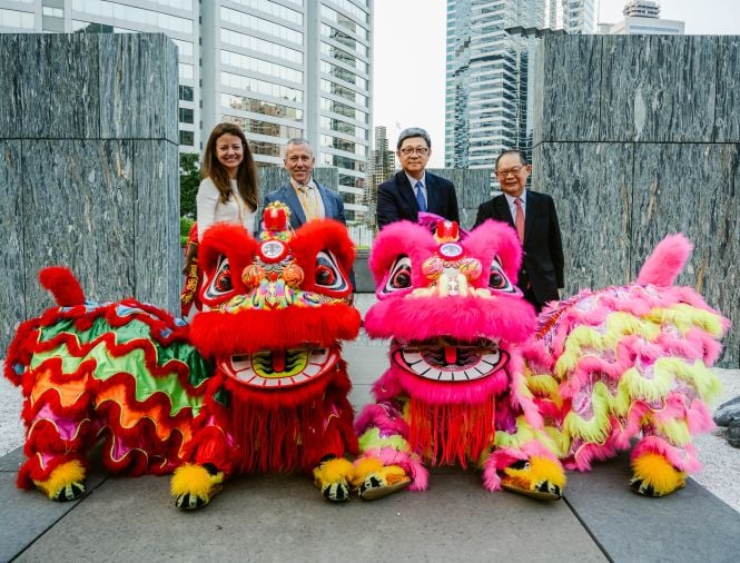 Four people stand behind Chinese dragon statues