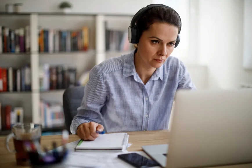 woman wearing headphones looking at a laptop