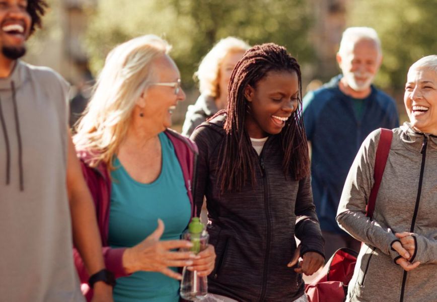 A diverse group of people walking and laughing together on a sunny day.