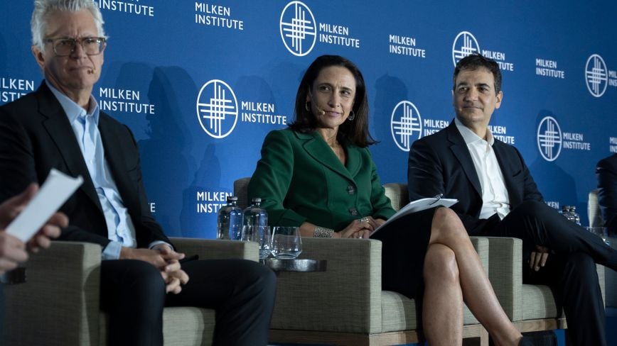Panelists at the Milken Institute Global Investors' Symposium Mexico City 2025. A man in glasses, a woman in a green blazer smiling, and a man in a white shirt and dark suit sit onstage against a blue Milken Institute backdrop.