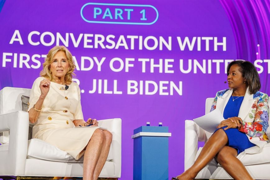 First Lady of the United States Jill Biden speaks on stage at the Milken Institute’s Future of Health Summit 2024, seated in conversation with a moderator in front of a purple backdrop displaying the session title “Part 1: A Conversation with First Lady of the United States Dr. Jill Biden.”