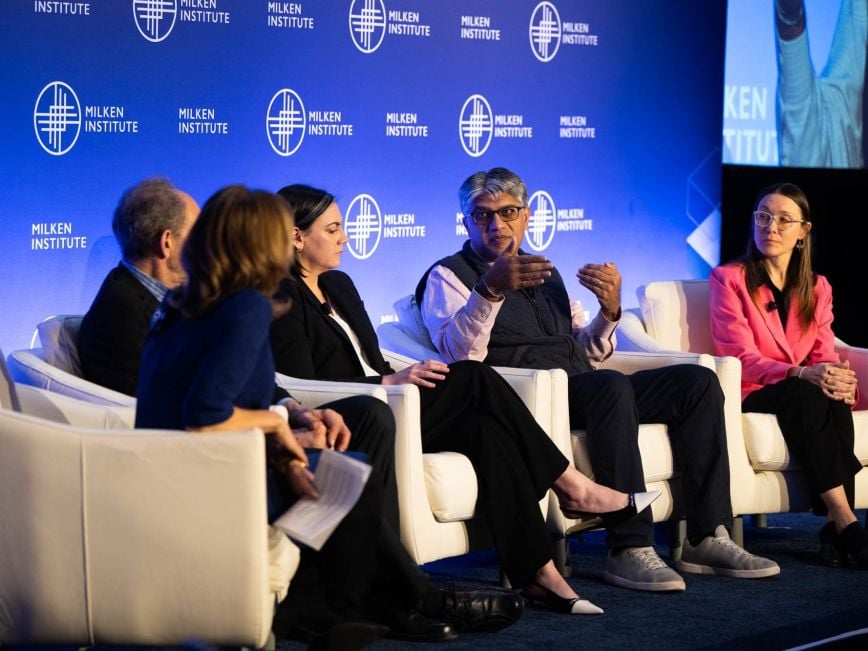 A panel of five experts engaged in a discussion at a Milken Institute event.