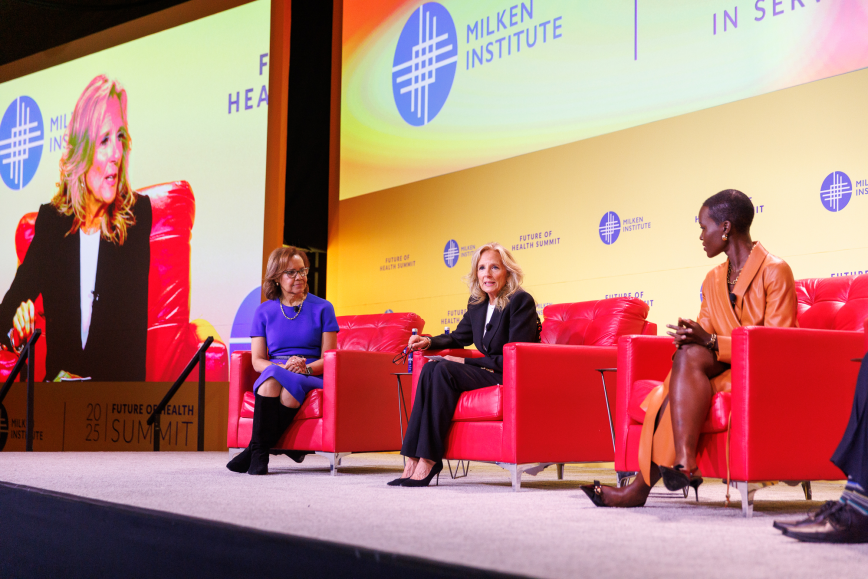 Jill Biden on stage seated in red chairs with colorful backdrop