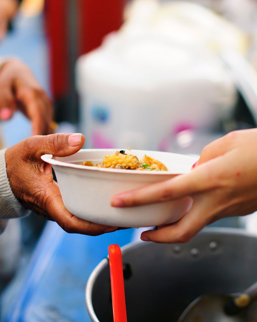An image of someone's hands, handing over a bowl of food to another person's hands.
