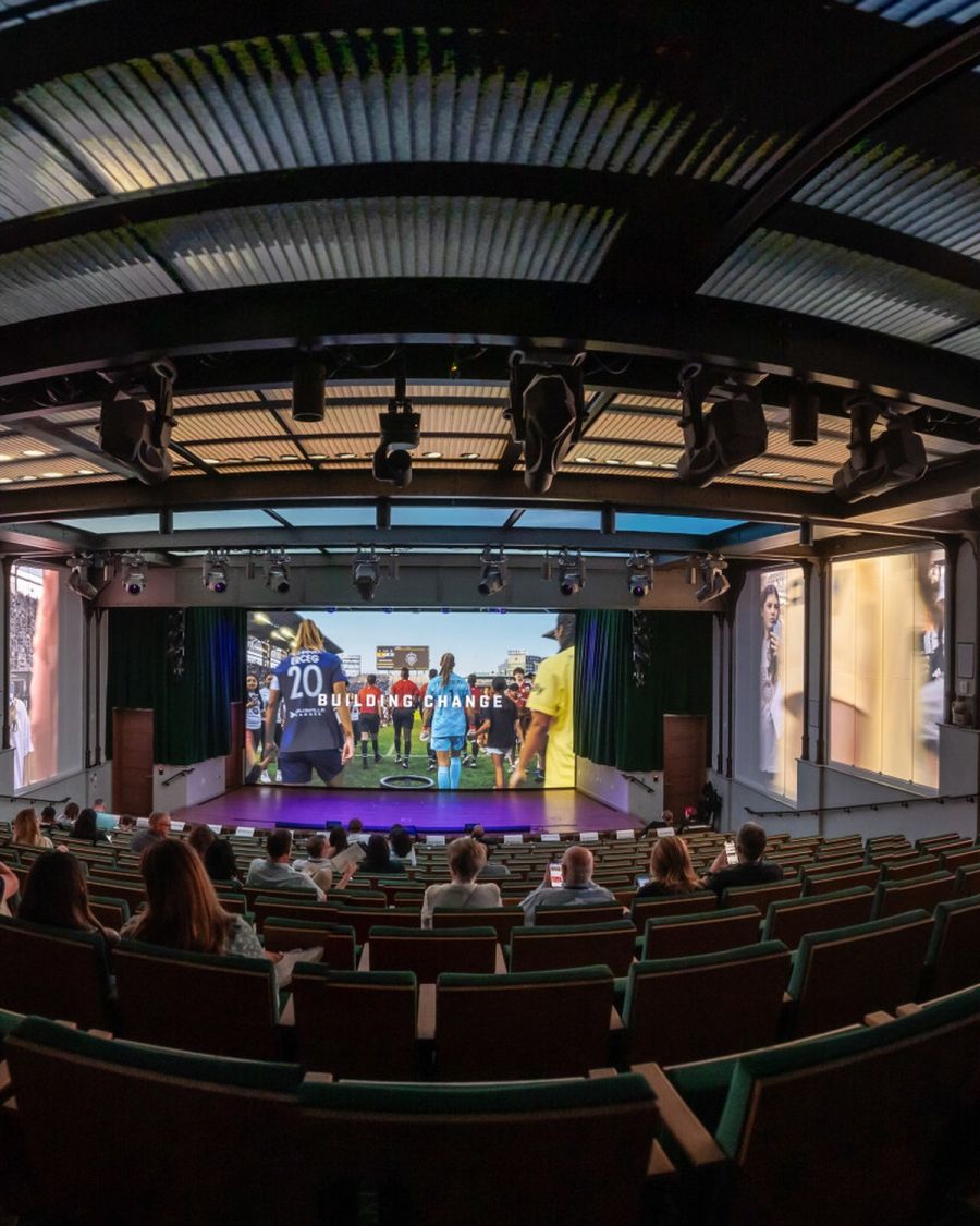 An audience watching a presentation on the theater's immersive wraparound screens