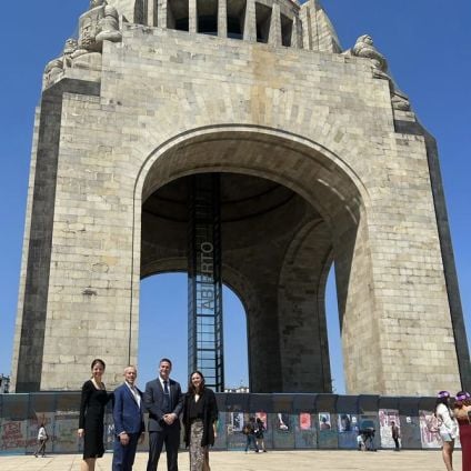 Four people pose outside an arch