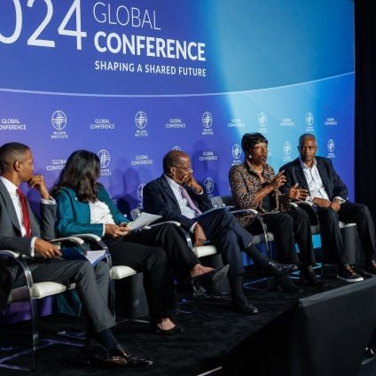 A group of panelists sit on stage during an event