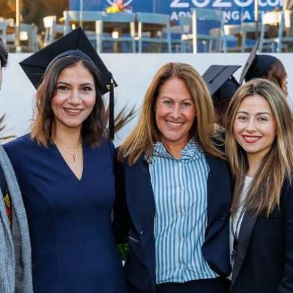 A group of people, some with graduation caps, pose together for a photo