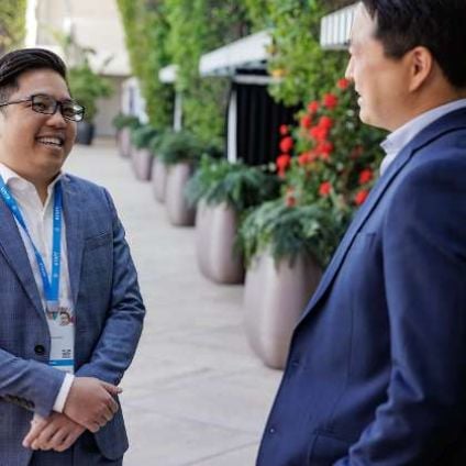 Two men network and laugh with each other at an outdoor reception