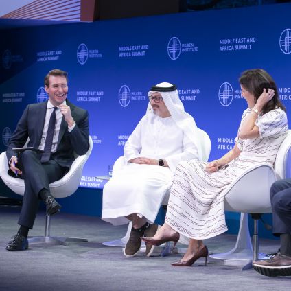 Three panelists sit on stage in discussion at the Middle East and Africa Summit, with the Milken Institute logo backdrop.