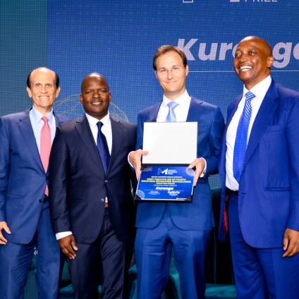 Four individuals in suits stand together on stage, one holding a certificate, during a recognition moment at the Middle East and Africa Summit.