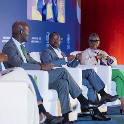 A group of panelists seated on stage in discussion at the Middle East and Africa Summit, with a branded backdrop behind them.