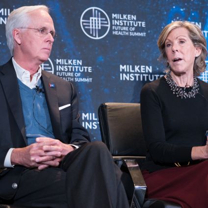 Two people in business attire holding folders at a Clinton Global Initiative event