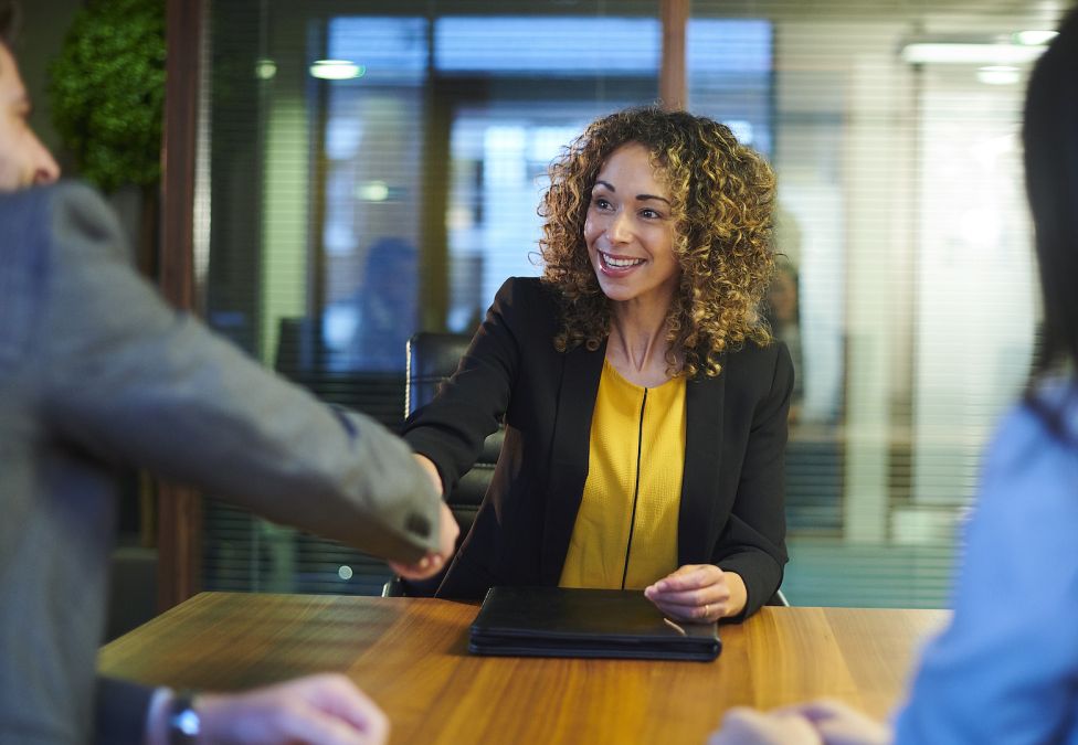 woman in a board room shaking someone's hand