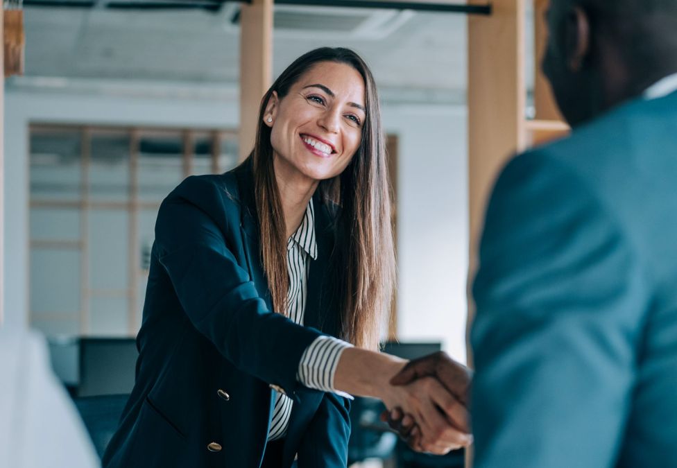 A woman and man shake hands in a business meeting.