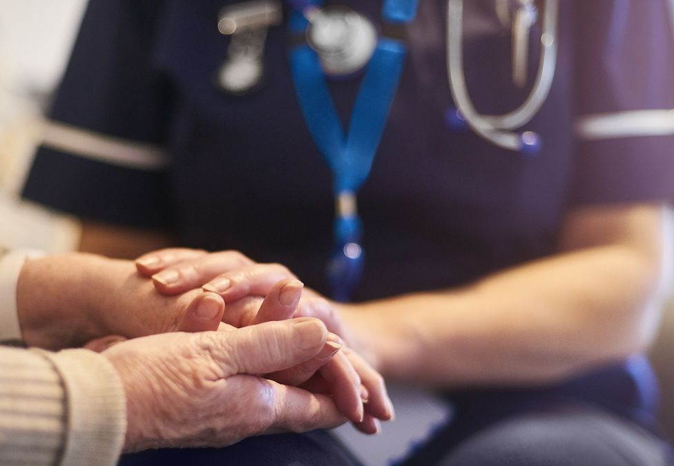 A nurse holds a patient's hands