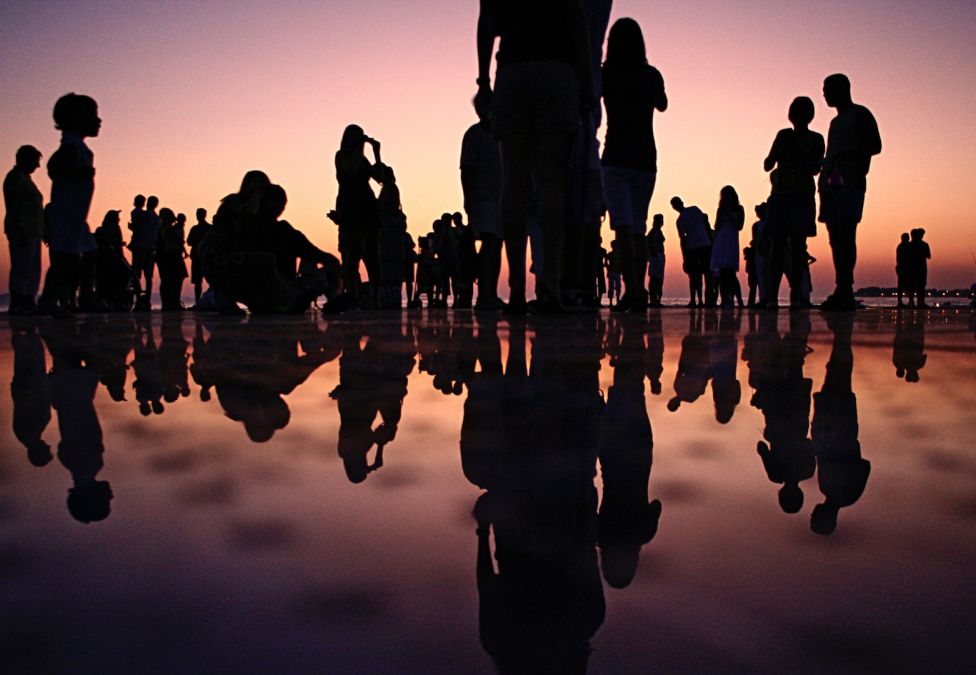 People's silhouettes on a beach during sunset