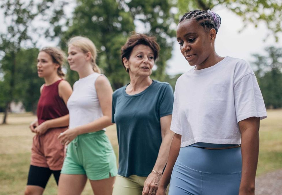 four people walking together in a park during the day