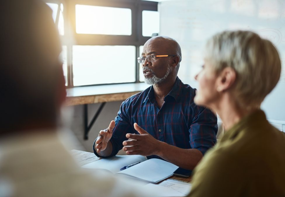 Three people sit at a table to have a conversation