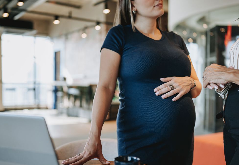 pregnant woman standing by a table with hand on her belly