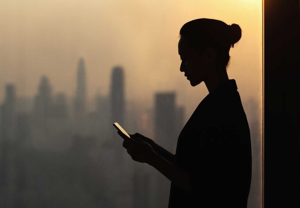 An image of a woman's silhouette wearing a bun and looking at her phone against a city skyline background, leading to an article titled "Global Insights: Opportunities for Government and Business to Advance Mental Health'.